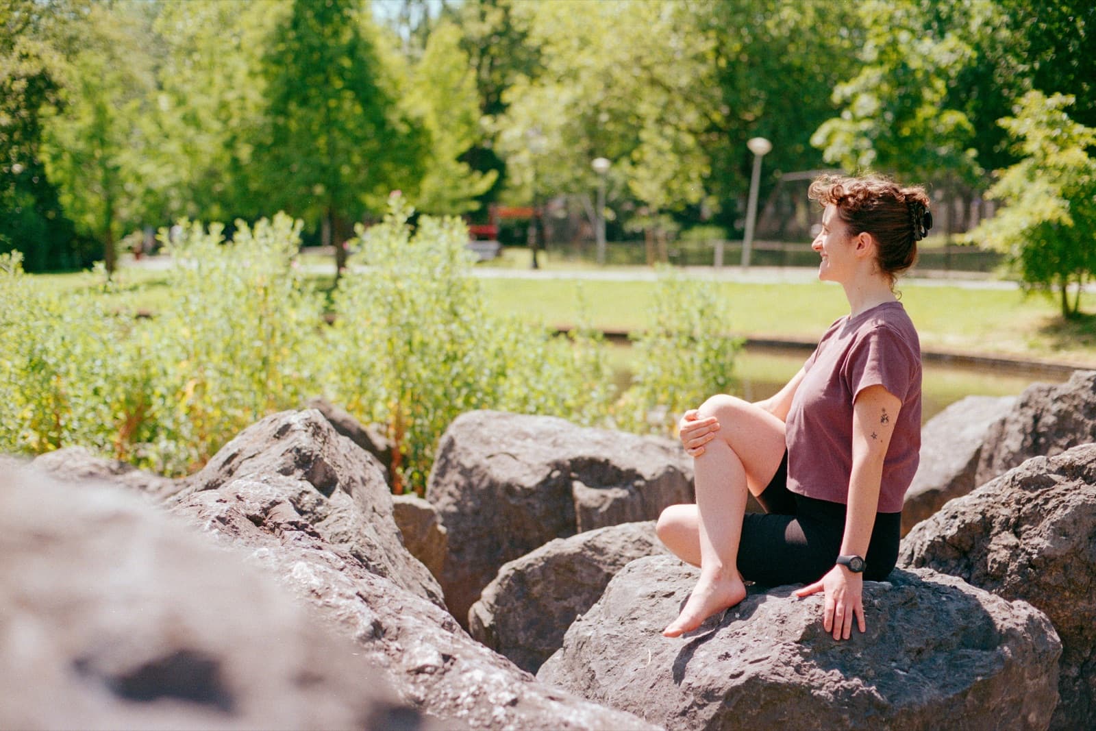 Vero sitting barefoot on rocks in the park, taking a quiet moment